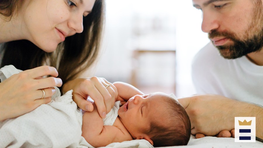 Two caretakers look down at an infant.