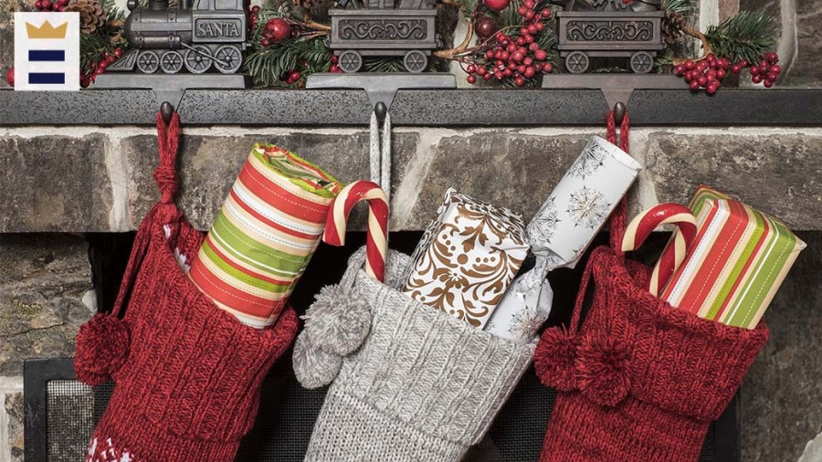 Three stockings with gifts in them hang from a fireplace.