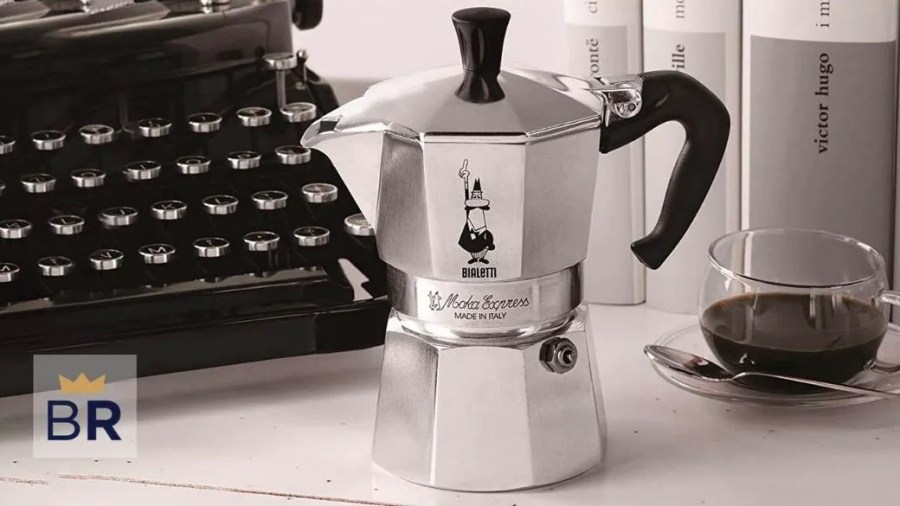 Moka espresso pot sitting on a desk in front of a typewriter and books