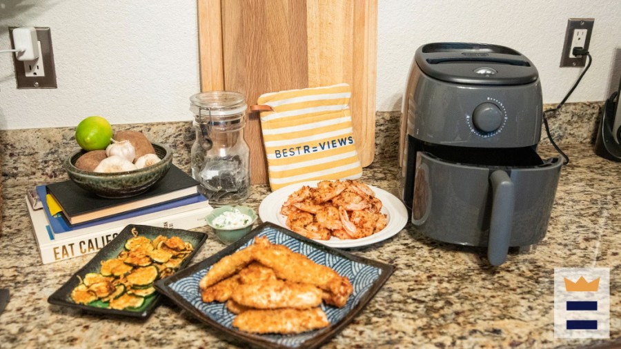 An air fryer on a counter along with several plates of food cooked inside it