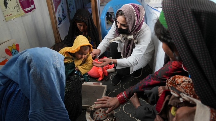 A nurse checks the weight of a child in a makeshift clinic organized by World Vision at a settlement near Herat, Afghanistan