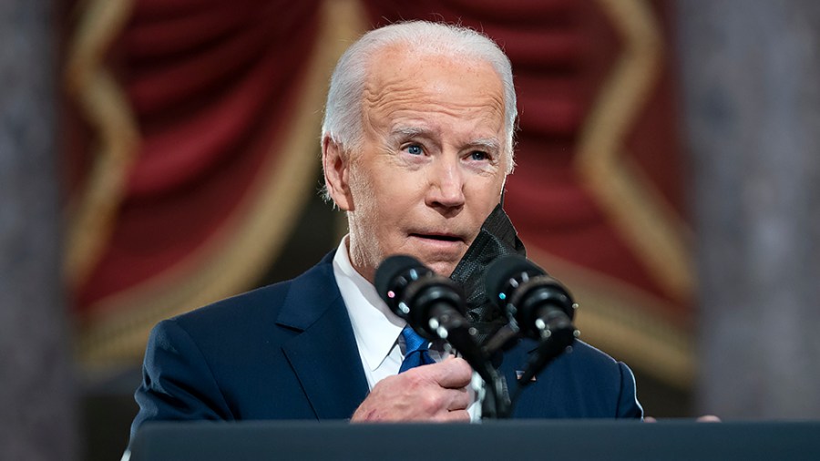 President Joe Biden removes his mask before giving remarks in Statuary Hall of the U.S Capitol in Washington, D.C., on Thursday, January 6, 2022 to mark the year anniversary of the attack on the Capitol.