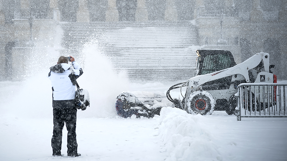 A person photographs Architect of the Capitol workers clear snow off the East Front Plaza of the Capitol during a snow storm on Monday, January 3, 2022. The Washington, D.C., area is forecasted to receive five to six inches of snow before the afternoon.