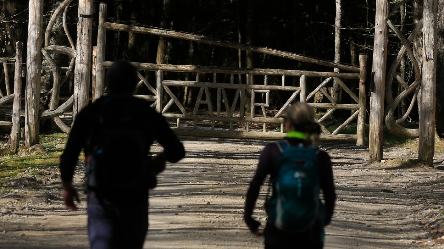 Two hikers approach the gated entrance to the Adirondack Mountain Reserve trailhead