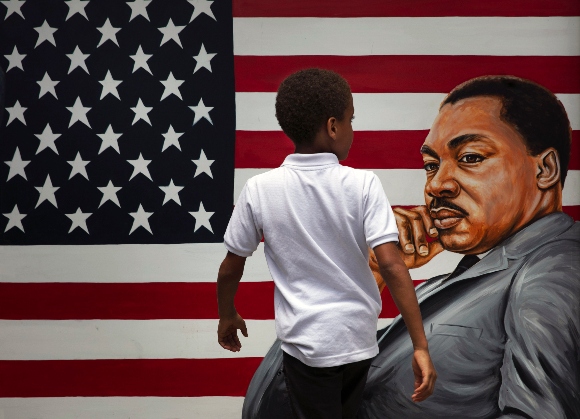 A young boy walks past a painting depicting Dr. Martin Luther King Jr. during a Juneteenth celebration in Los Angeles