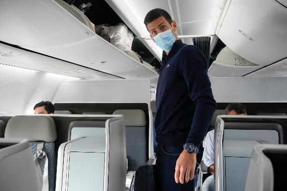 Novak Djokovic prepares to take his seat on a plane to Belgrade