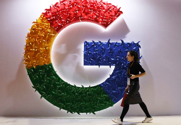 A woman walks past the logo for Google at the China International Import Expo in Shanghai