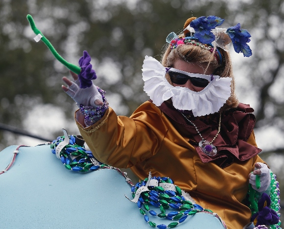 A masked rider in the Iris Mardi Gras parade throws beads