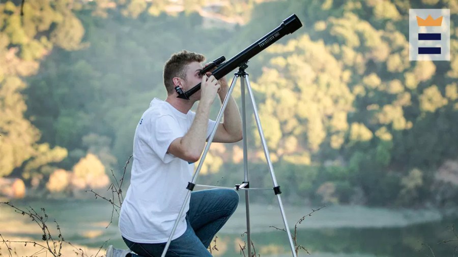 Man outside looking through a telescope