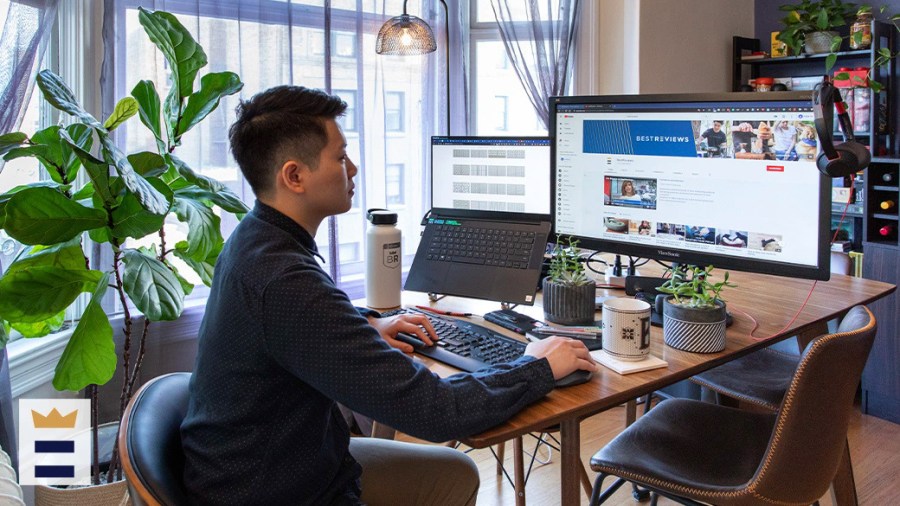 Person working from home using a laptop and a large secondary display monitor