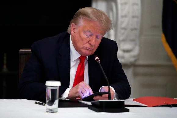 President Donald Trump looks at his phone during a roundtable with governors