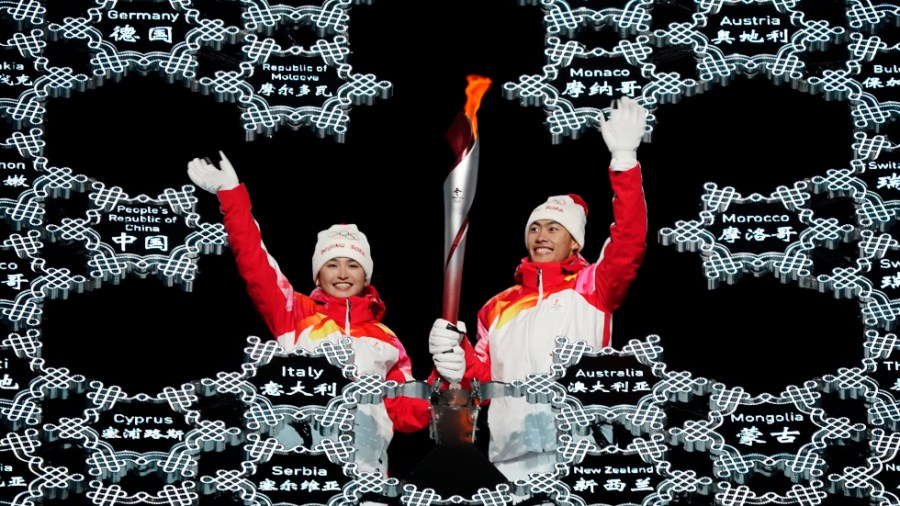 The 2022 Winter Olympics torch is brought into the Beijing stadium by Dinigeer Yilamujian and Zhao Jiawen