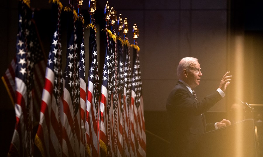 President Joe Biden is seen speaking with multiple American flags behind him