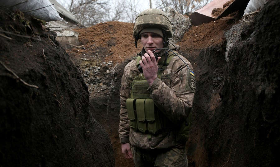 A service member of Ukrainian military forces speaks surrounded by dirt