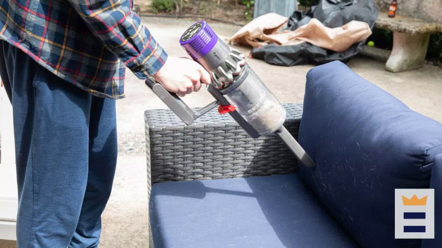 Person cleaning pet hair off of a couch using a handheld cordless vacuum