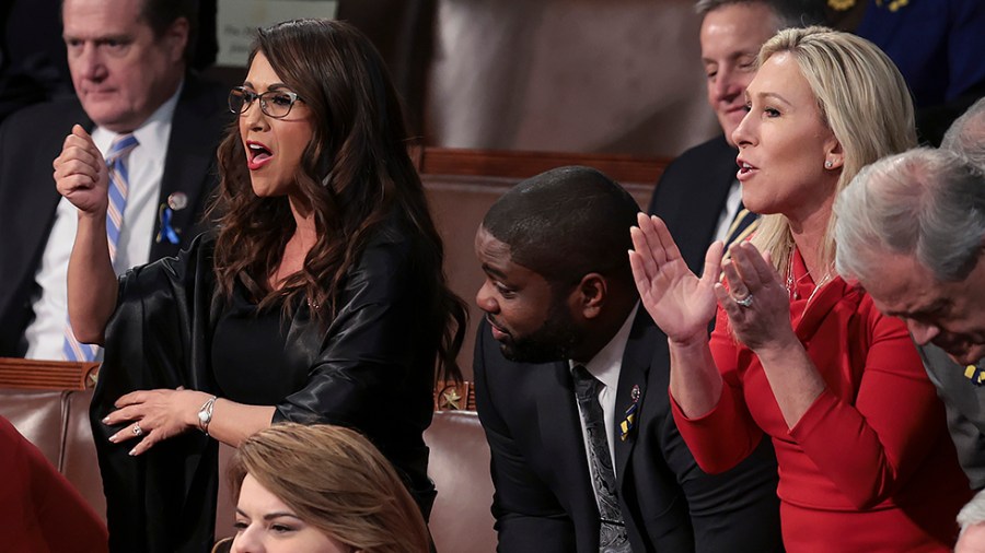 Reps. Lauren Boebert (R-Col.) and Marjorie Taylor Greene (R-Ga.) stand with fellow lawmakers as they listen to President Biden's State of the Union address on Tuesday, March 1, 2022.