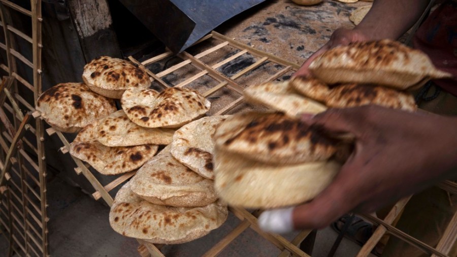 A worker collects Egyptian traditional 'baladi' flatbread, at a bakery, in el-Sharabia, Shubra district, Cairo, Egypt