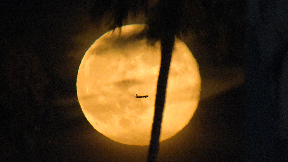 A plane flies past a supermoon