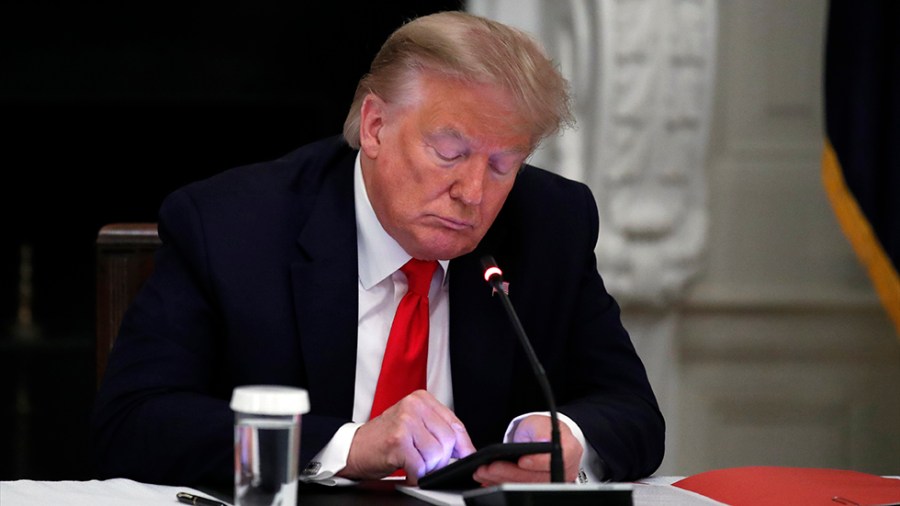 President Trump looks at his phone during a roundtable with governors