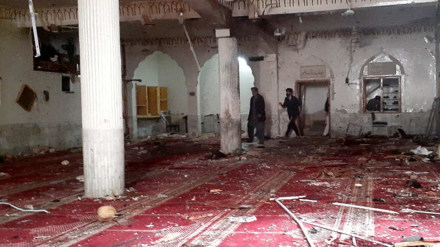 Volunteers examine the site of explosion inside a Shiite mosque in Peshawar, Pakistan