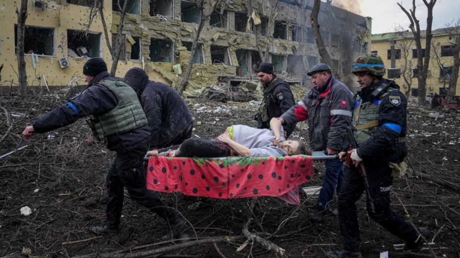 Ukrainian emergency employees and volunteers carry an injured pregnant woman from a maternity hospital that was damaged by shelling in Mariupol, Ukraine