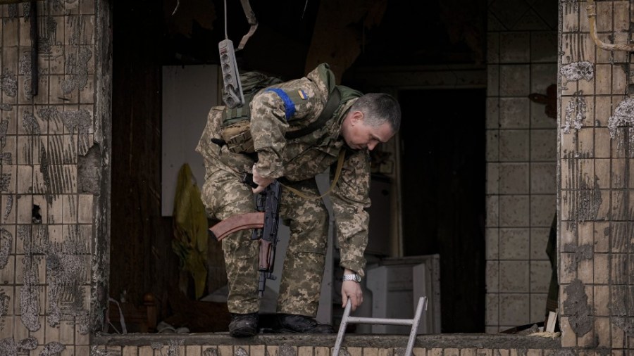 A Ukrainian member of the territorial defense exits through the window of an apartment in a block which was destroyed by an artillery strike in Kyiv, Ukraine