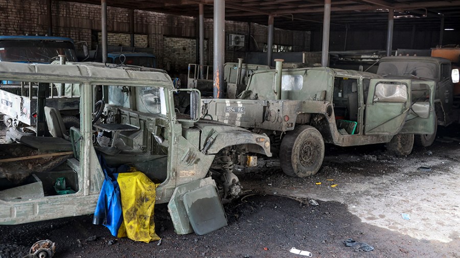 Damaged Ukrainian army military vehicles with a Ukrainian national flag are seen