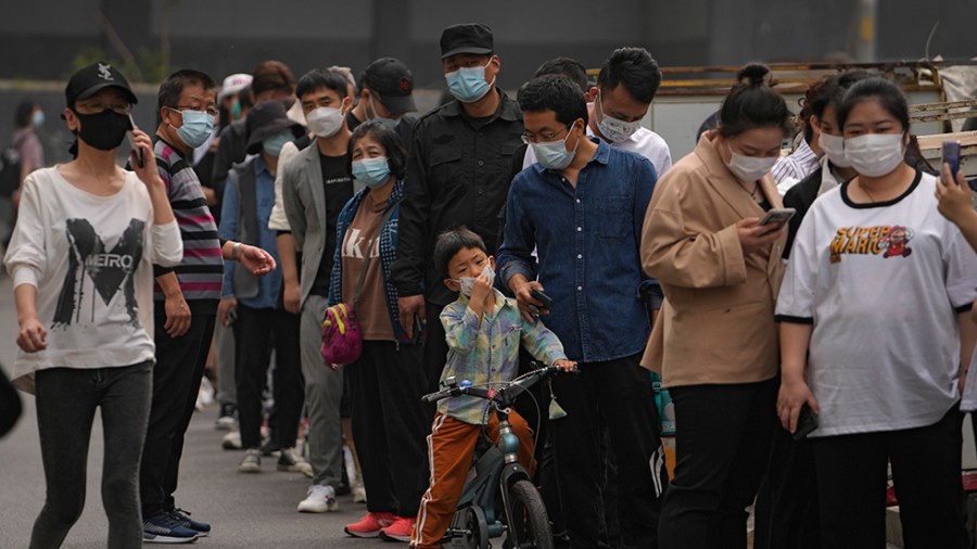 Residents and office workers wearing face masks line up for mass coronavirus testing