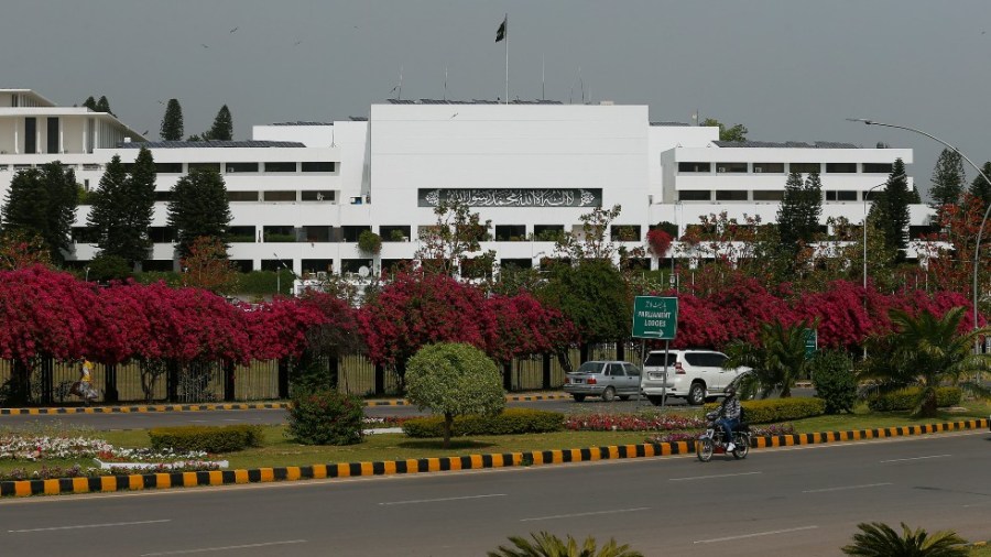 A motorcyclist rides past the National Assembly where the session to choose the new prime minister continues in Islamabad