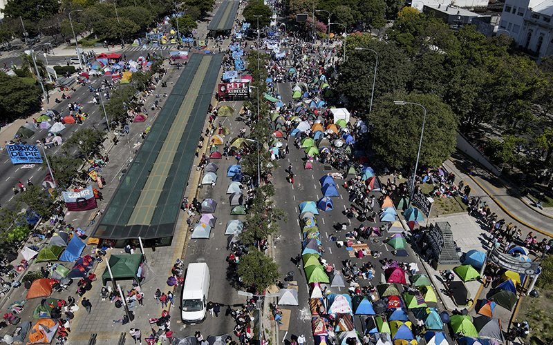 People camp in multi-colored tents on a road avenue