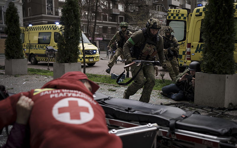 Ukrainian servicemen run for cover as they pass ambulances