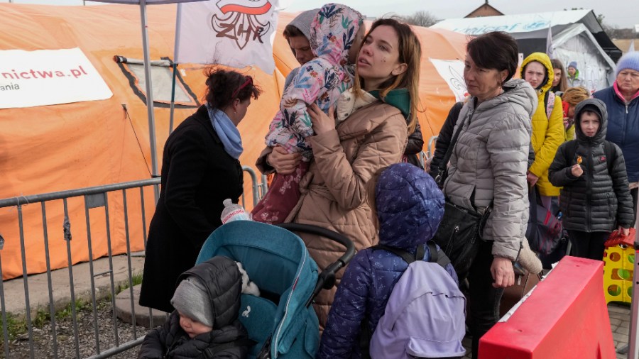 Refugees wait in a line after fleeing the war from neighboring Ukraine at the border crossing in Medyka, southeastern Poland