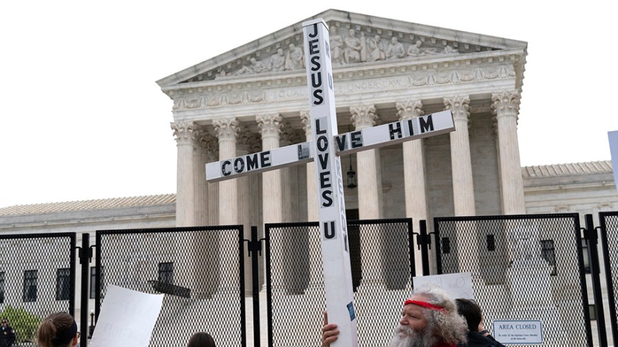 A demonstrator holding a cross protests outside the U.S. Supreme Court