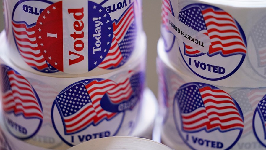 Rolls of stickers that read "I voted" sit on a table