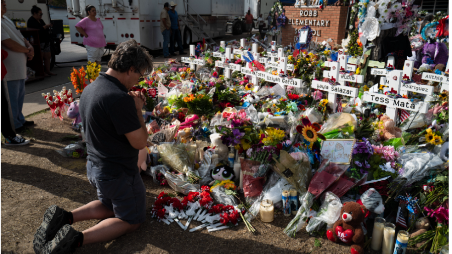 A man kneels in front of a memorial at Robb Elementary School in Uvalde, Texas.