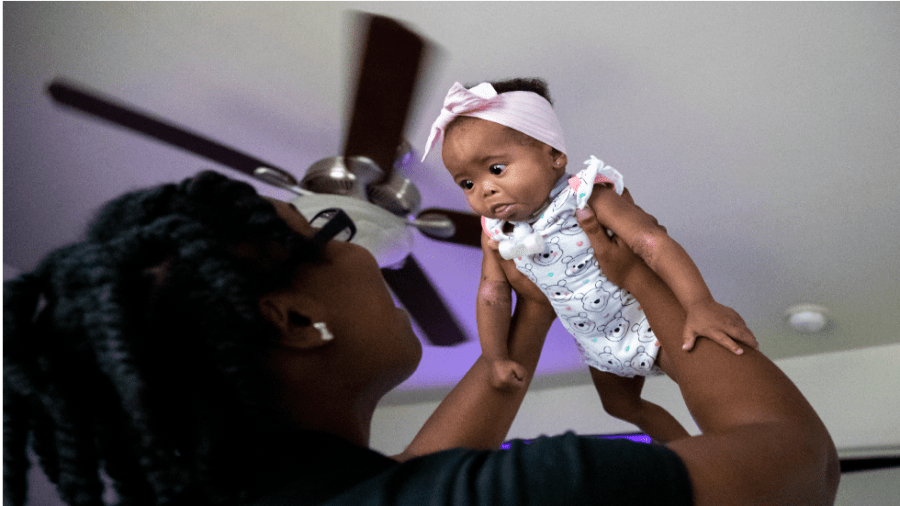 A mother lifts her daughter into the air.