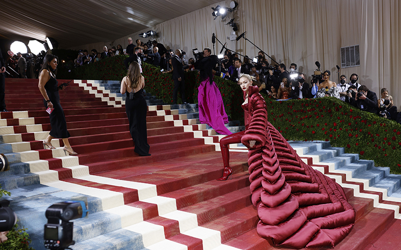 Gigi Hadid arrives on the red carpet for the Met Gala in a long red gown