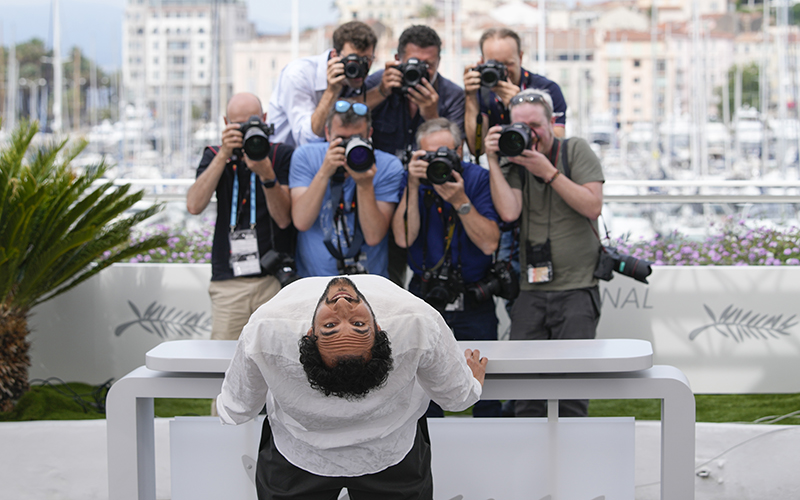 Director Ali Abbasi poses for photographers as he bends backwards to face another camera