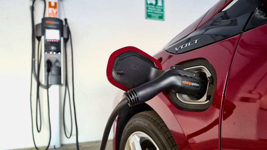 A red Chevrolet Volt hybrid car charges at a ChargePoint charging station at a parking garage