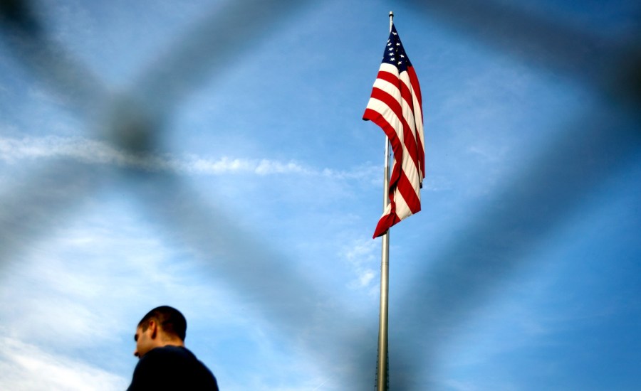 Man walks in front of flag.