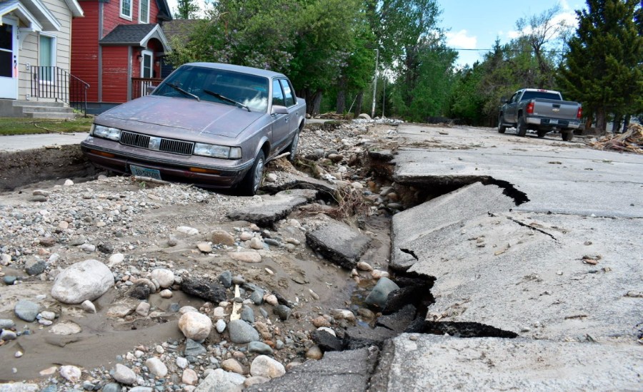 street with damaged pavement with car in background