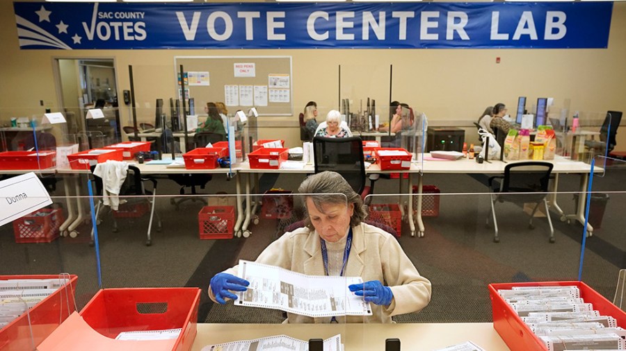 Election worker inspects a mail-in ballot for damage