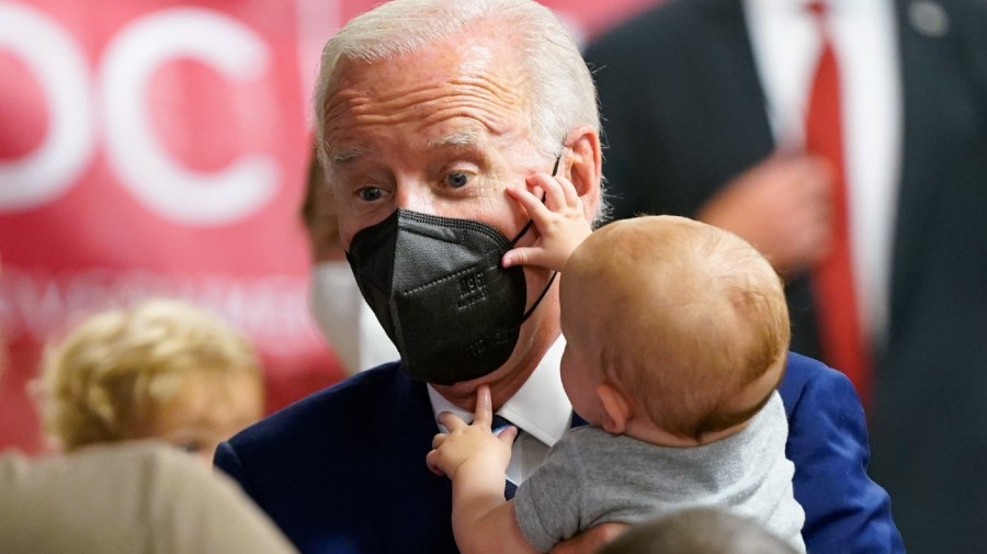 President Joe Biden holds a baby as he visits a COVID-19 vaccination clinic