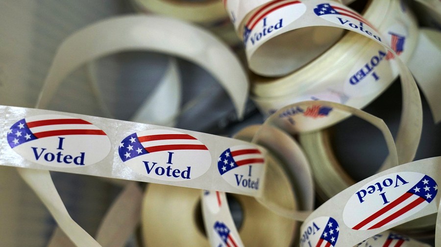 Rolls of "I voted" stickers litter a table.