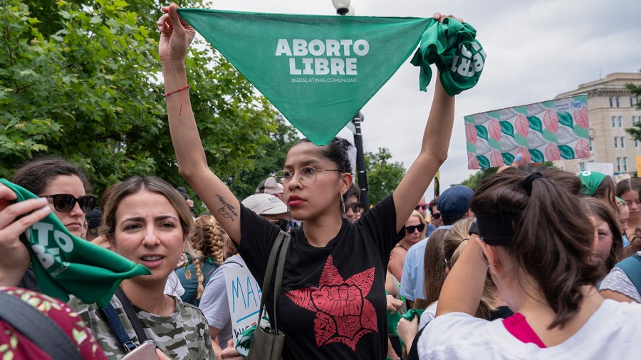 A woman holds up a bandana saying "aborto libre" in Spanish