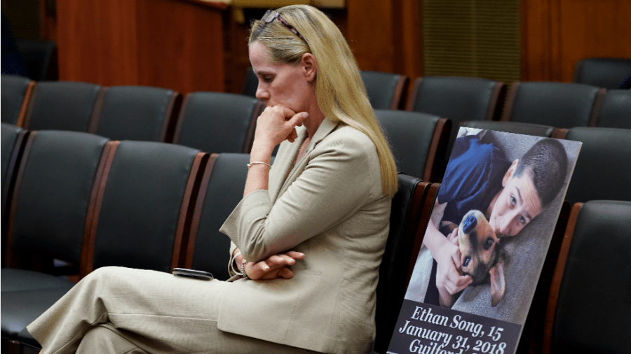 A woman sits beside a picture memorializing her son.