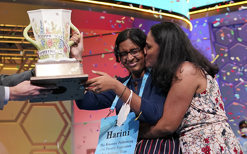 Harini Logan, 14, from San Antonio, Texas, gets a kiss from her mom as she receives the Scripps National Spelling Bee trophy