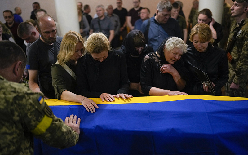 Relatives of Army Col. Oleksander Makhachek mourn over his Ukrainian flag-draped coffin