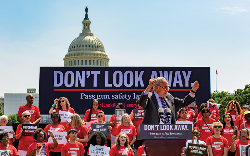 Senate Majority Leader Charles Schumer speaks at a gun safety in front of a banner that says, "Don't Look Away, pass gun safety laws"