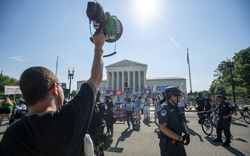 An abortion rights supporter holding a mega-phone confronts anti-abortion activists who are surrounded by police